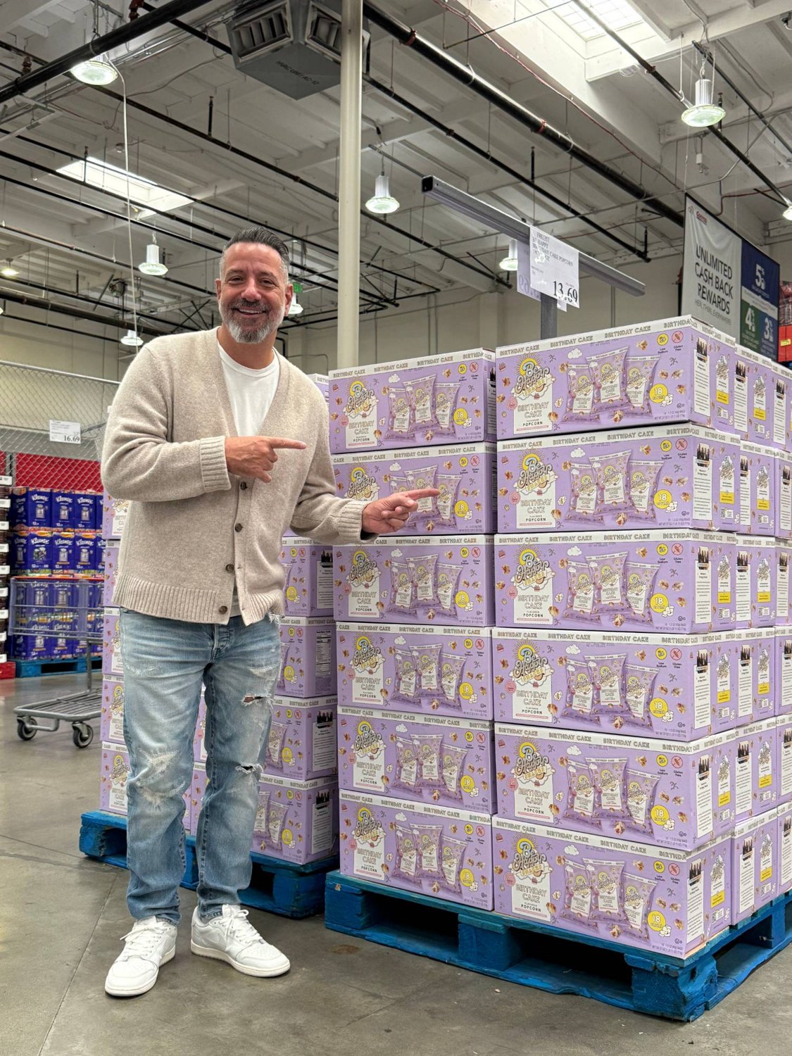 Marc D'Amelio with a pallet of Be Happy Snacks Birthday Cake popcorn on the Costco floor