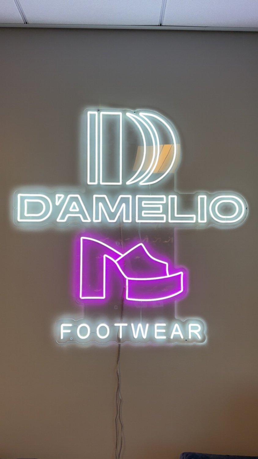 The D'Amelio Footwear neon sign at the office